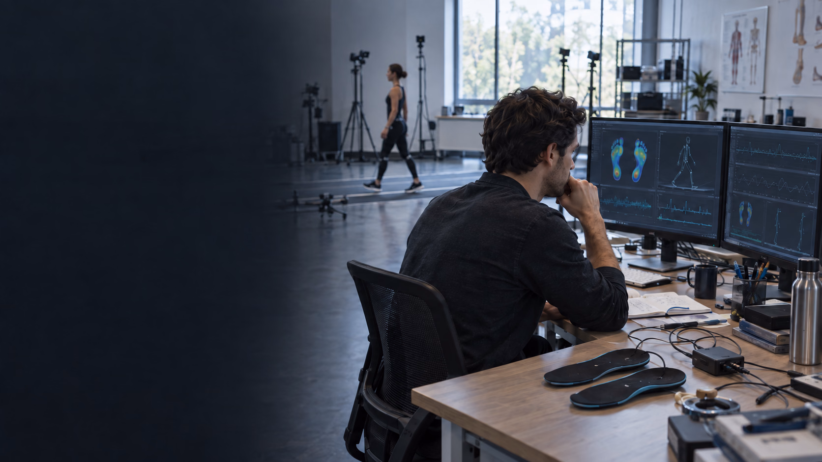 An engineer reviewing movement and plantar-pressure data while a participant walks through a biomechanics lab